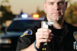 A Police Officer Holds a Breath Test Machine — Waukegan, IL — Daniels, Long & Pinsel, LLC